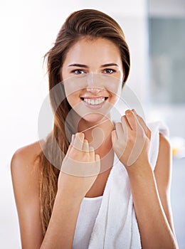 She knows the importance of flossing. Portrait of an attractive young woman holding dental floss and smiling.