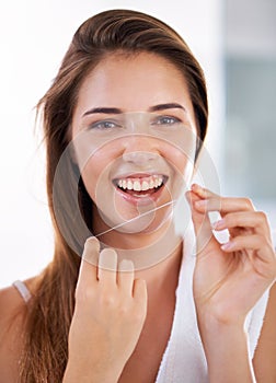 She knows the importance of flossing. Portrait of an attractive young woman holding dental floss and smiling.