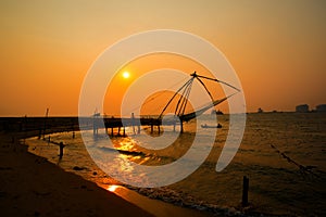 Kochi chinese fishnets and the boat with fishermen on sunset