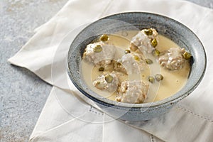 Koenigsberger Klopse or boiled meatballs in a white bechamel sauce with capers, traditional Polish and German dish in a gray bowl photo