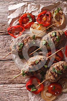 Kofta kebab with grilled vegetables close-up on the table. vertical top view, rustic