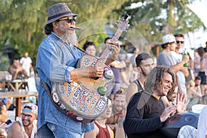 Street musicians playing guitar and handpan for tourists at sunset on the beach in island Koh Phangan, Thailand