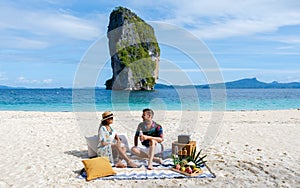 Koh Poda Beach Krabi Thailand, a couple of men and woman on the beach picnic with fruit and drinks