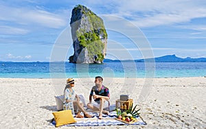 Koh Poda Beach Krabi Thailand, a couple of men and woman on the beach picnic with fruit and drinks