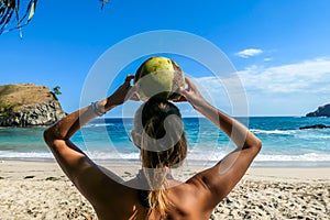 Koka Beach - A girl holding a coconut on her head with the beach view