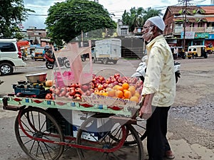 Stock photo of 50 to 60 year old Indian fruit seller selling fresh fruits like apple , orange etc