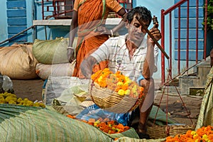 Indian seller weighs flowers by scales on Flower market at Mallick Ghat in Kolkata. India