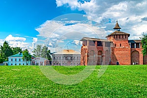 Kolomna kremlin red brick wall adn old houses along green grass. Brickwork wall of the Kolomna Kremlin against blue dramatic cloud photo