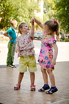 Two little girls holding hands dancing on a city holiday