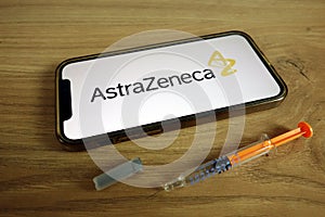 KONSKIE, POLAND - June 9, 2021: AstraZeneca plc logo on mobile phone with syringe. Covid-19 vaccine concept