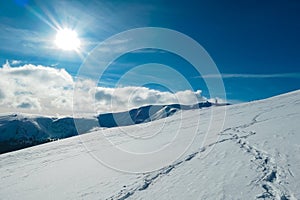 Kor Alps - Snow shoe prints on idyllic snow covered alpine meadow with scenic view of mountain peak Grosser Speikogel