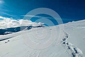 Kor Alps - Snow shoe prints on idyllic snow covered alpine meadow with scenic view of mountain peak Grosser Speikogel