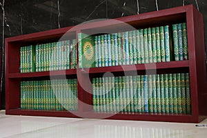 The Koran is neatly arranged on a wooden shelf photo