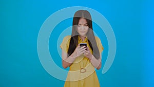 Korean, asian woman reads news carefully isolated on dark blue background, girl hol phone, copy space 4K