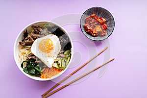 Korean bi bim bap and kimchi with chopsticks on pink background. Top view