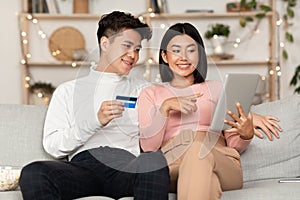Korean Couple Shopping Online Via Tablet And Credit Card Indoor