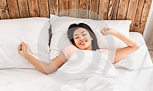 Korean Girl Waking Up Lying In Bed Stretching Hands, Above-View
