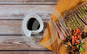 Korean grilled beef and mushrooms, soy sauce, on board with chopsticks