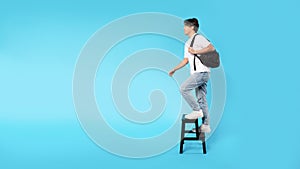 Korean Guy Walking Up Stairs On Ladder Over Blue Background