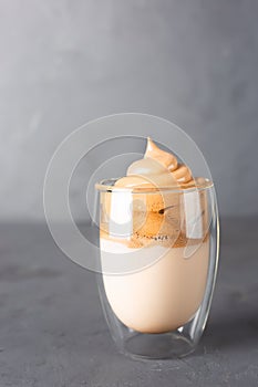 Korean iced Dalgona coffee in glass on a grey table. Trendy fluffy creamy whipped coffee photo