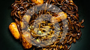 Korean instant noodle in black plate on wood table for food content