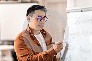 Korean Male Teacher Having Class Writing On Whiteboard In Classroom