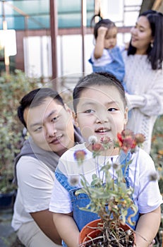 Korean man and his charming wife with cute children are buying green planters home
