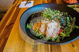 Korean mixed rice with meat, Bibimbap, with vegetables on a black bowl