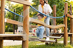 Korean Mom Engaging With Toddler in Playground Adventure in Park