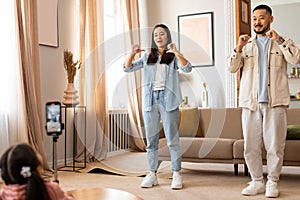 Korean parents and daughter shooting video on smartphone at home