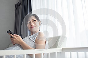 Korean pregnant woman smiling sitting on bed