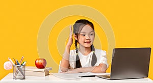 Korean Schoolgirl Raising Hand Sitting At Laptop Computer In Studio