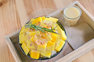 Korean style fresh mango shaved ice on wood table .