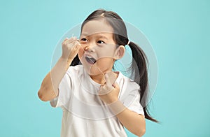Korean sweet little girl cleaning his teeth with a dental floss on blue isolated.
