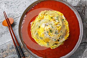 Korean swirl omelette tornado on top of fried rice and hot sauce close-up in a plate. Horizontal top view