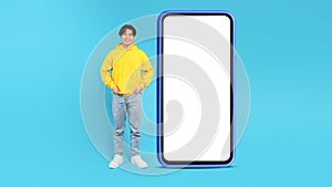 Korean Teen Guy Near Big Phone Standing On Blue Background