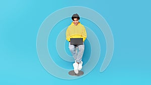 Korean Teen Guy Using Laptop Sitting Over Blue Studio Background