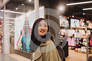 Korean teenage girl choosing and buying trendy clothes in a shopping mall. Retail and consumerism. Sale promotion and shopping