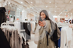 Korean teenage girl choosing and buying trendy clothes in a shopping mall. Retail and consumerism. Sale promotion and shopping