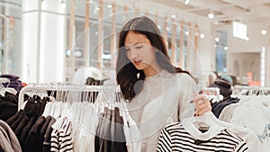 Korean teenage girl choosing and buying trendy clothes in a shopping mall. Retail and consumerism. Sale promotion and shopping