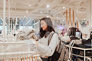 Korean teenage girl choosing and buying trendy clothes in a shopping mall. Retail and consumerism. Sale promotion and shopping