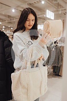 Korean teenage girl choosing and buying trendy clothes in a shopping mall. Retail and consumerism. Sale promotion and shopping