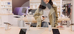 Korean teenage girl choosing phone at technology store. Female customer viewing smart phones in store. Retail and consumerism.