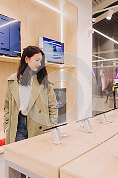 Korean teenage girl choosing phone at technology store. Female customer viewing smart phones in store. Retail and consumerism.