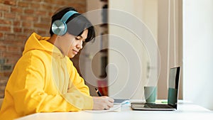 Korean Teenager Boy At Laptop Taking Notes Learning At Home