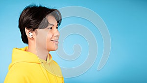 Korean Teenager Boy Wearing Earbuds Earphones Over Blue Background