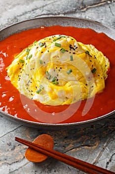 Korean tornado omelette over fried rice and hot sauce closeup on the plate. Vertical