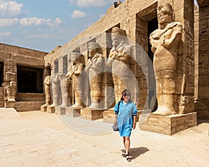 Korean tourist and Osiride sculptures of King Ramesses III in the courtyard of his temple in the Karnak temple complex.