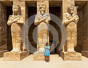 Korean tourist and Osiride sculptures of King Ramesses III in the courtyard of his temple in the Karnak temple complex.