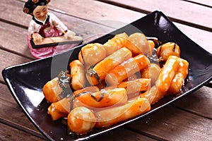 Korean Tteokbokki with chili sauce on black platter photo